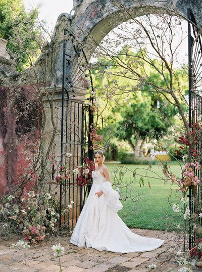 Bride poses next to ornate gate at her destination wedding