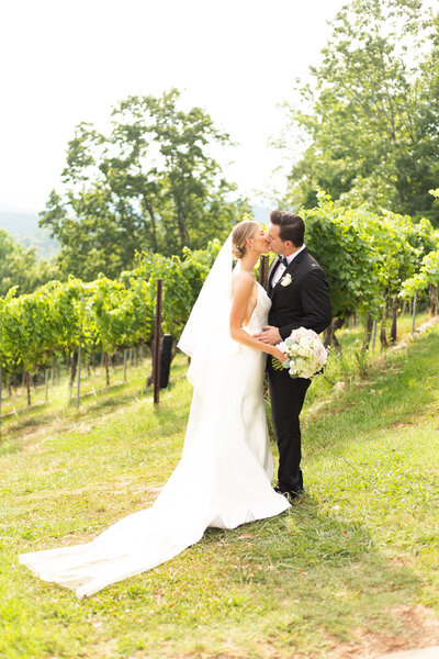 bride and groom kissing at a vineyard