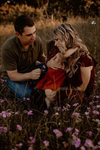 Family photography near Dayton TX - parents playing with toddler in grassy outdoor field