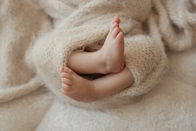 Newborn’s feet wrapped in cozy blanket by a Michigan photographer