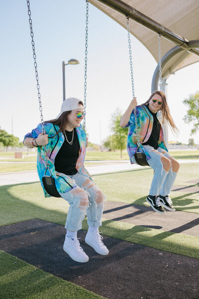 Two people on swings in a park.