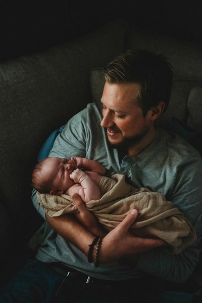 Portrait of dad holding a swaddled newborn baby