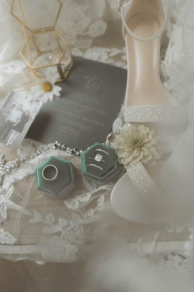 detail wedding photograph of flat lay wedding rings and wedding shoes, and wedding invitation taken at montagu meadows wedding venue in westminster maryland