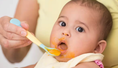 baby eating food in high chair 