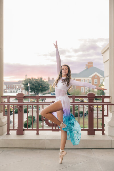 Senior girl in pointe shoes dances on pointe in front of the palladium in Carmel, Indiana