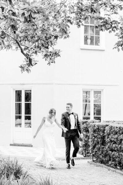 candid black and white photo of bride & groom entering their reception