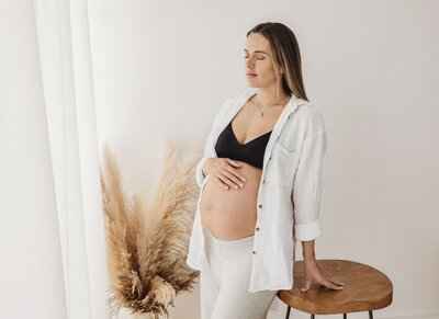 Pregnant woman by window with pampas grass. Altrincham maternity.
