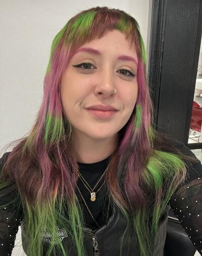 Image of owner of Good Mood Hair Shop with hair that has been dyed pink and green.