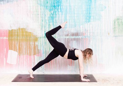 Woman doing yoga pose in front of colorful wall