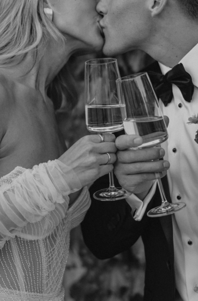 BW Photo of kissing couple with flutes of champagne