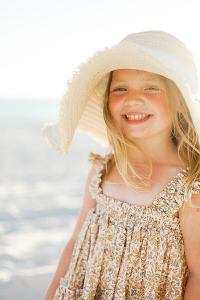 Little girl wearing her moms sunhat during a family beach session in DFW.