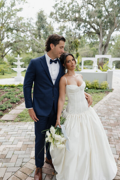 Bride and groom walking together at Uliana Estate wedding venue in Lakeland, Florida, surrounded by lush trees and elegant garden pathways