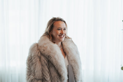 Woman looks into the distance wearing a big fur coat