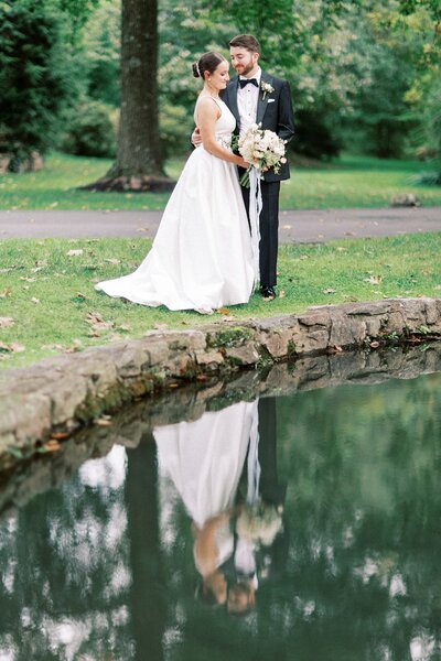 Bride and groom pose by reflection pond