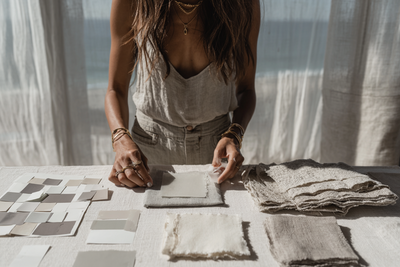 Close-up of a designer arranging neutral fabric swatches and color samples on a table, representing the hands-on creative process during a Studio VIP Day with Kathalyst Design Studio.