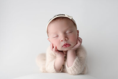 Elegant and clean studio portrait of a newborn baby in the beloved froggy pose, highlighting pure simplicity.
