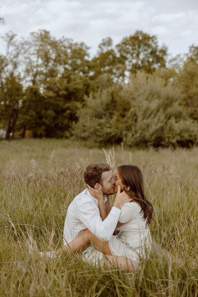Sitting in a field at Terrapin Beach on Kent Island, this couple shares a kiss during their couple photoshoot. 