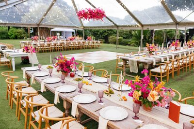 Long wedding reception tables under a clear tent 