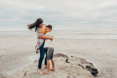 A mother and son hug in front of the occean in San Diego