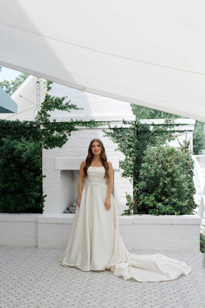 A bride standing in front of a fireplace in her wedding dress at Little Point Clear Venue in Fairhope, Alabama.