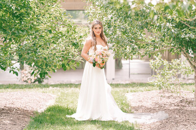 A blonde bride holding a colorful wedding bouquet at Haven Farms enjoying her destination wedding photos by JoLynn Photography