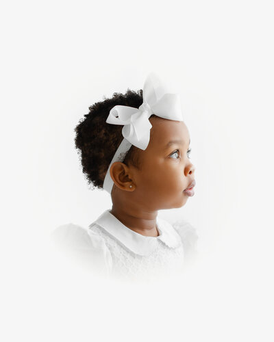 A photo of a sweet boy smiling at the camera wearing a smocked white collared shirt during his heirloom portraits photo session