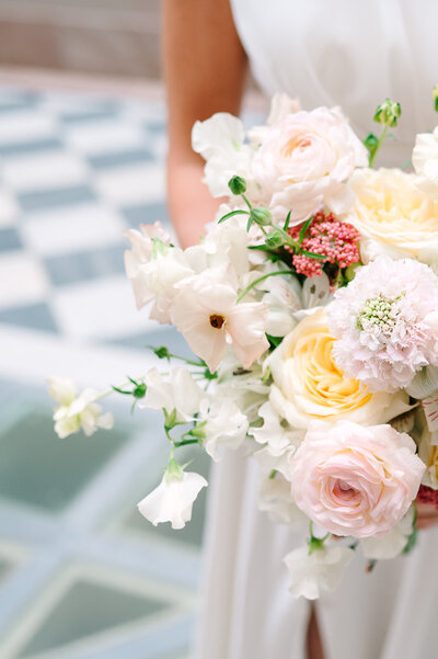 a bride standing in front of an alcove holding a bouquet