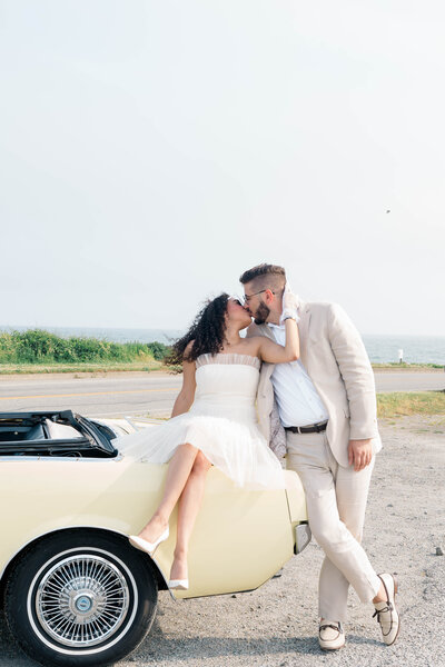 Newport Wedding Photographer | Rhode Island Caprio Captured Photography | Couple Kissing While The Woman Is Sitting On A Trunk of A Vintage Car