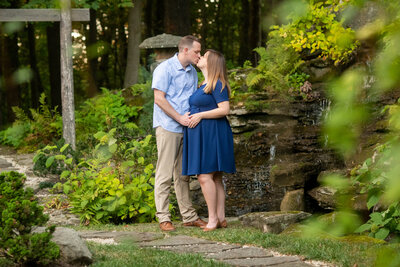 Pregnant couple snuggles at Stan hywet garden