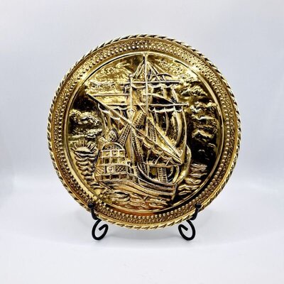 Vintage brass decorative plate with embossed tall ship design on black metal stand