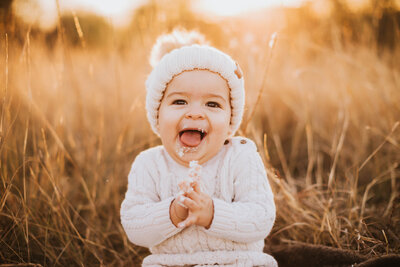 baby girl in a matching crochet outfit and hat outfit backlit in a pretty field