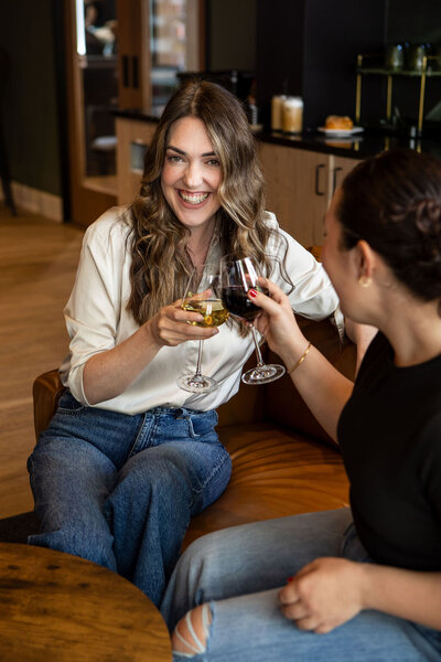 Two women cheering with red and white wine