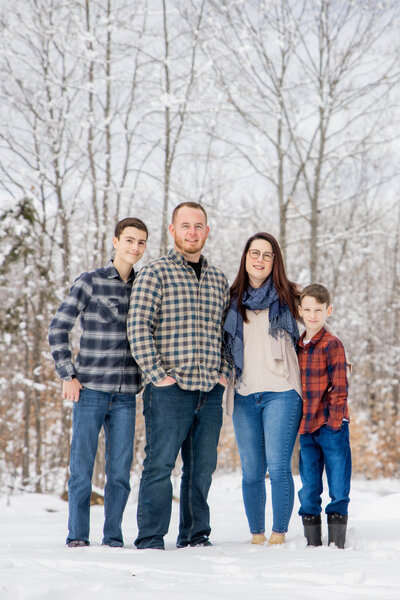Family in the snow with tress in the back | Family Session Taken by Maine Photographer