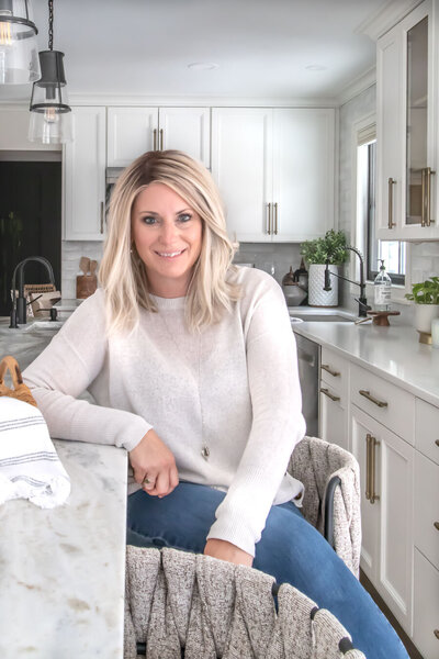 SC interior designer Priscilla Ertel sits in a bright kitchen with marble countertops she designed through her company, Haven + Harbor