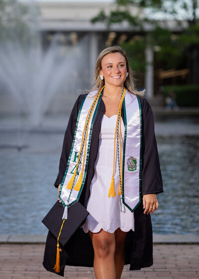 A ​University of South Carolina student taking her senior portrait​s in ​o​n campus in front of the Thomas Cooper Library fountain.