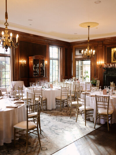 November wedding at Graylyn Estate, designed and planned by Charming Carolina — wide view of the Living Room set for reception dinner with round tables, centerpieces, and warm candlelight.