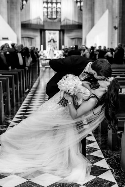 Groom kissing bride in aisle after Detroit wedding ceremony