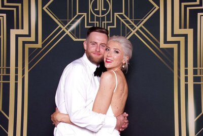 beautiful couple posing front of a really cool gatsby backdrop
