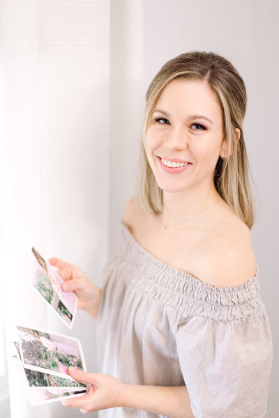 A Cincinnati maternity photographer holding printed pictures