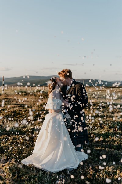 A newly married couple kiss at Cairn o Mount in Aberdeenshire as confetti is photographed all around them.
