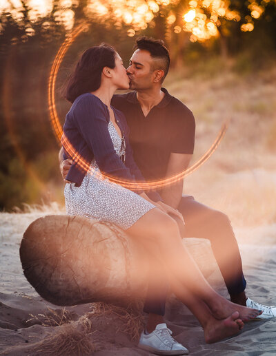 A newly engaged couple kissing at the viewpoint in Discovery Park in Seattle, WA. Beautiful, golden ring of fire effect overlays the photograph.