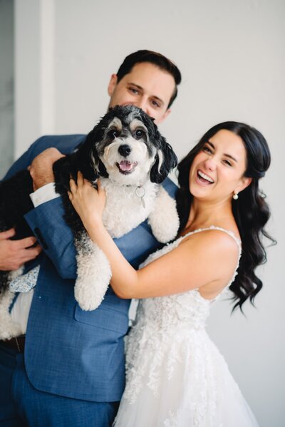 bride and groom holding puppy on wedding day