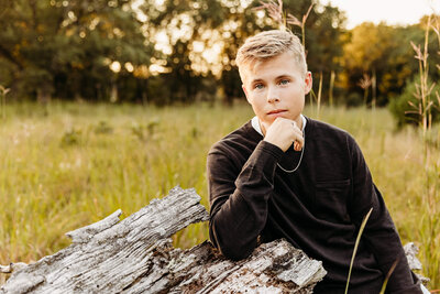 high school senior boy sitting on a log posing for his senior photo session