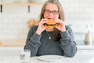 Amanda takes a bite out of a cheeseburger, showcasing how personal branding uses aspects of your personality to embellish your brand