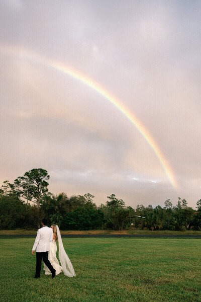 bride and groom walking under a rainbow by Wedding Photographer South Florida