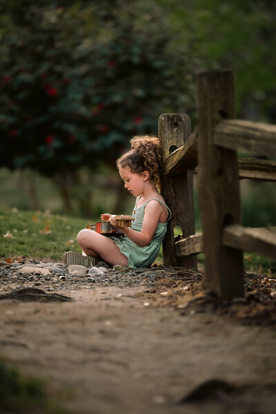 photo of a girl sitting against a fence during spring minis in sacramento
