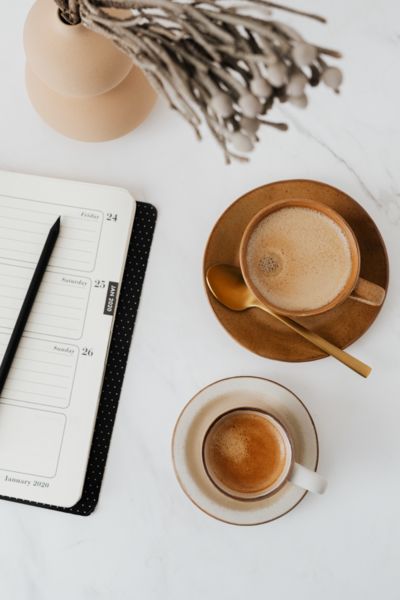 Desktop view of planner and pen and two cups of coffee | Brand By Design
