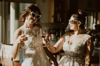 Two brides toast champagne during their Dillon Beach elopement
