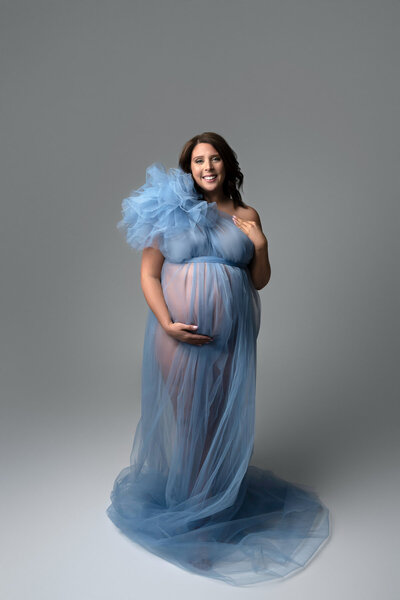 Light blue maternity gown with tulle overlay and structured shoulder detail – styled for clean studio photo