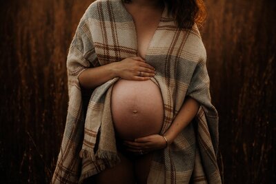 Outdoor photo of pregnant mother wearing a blanket